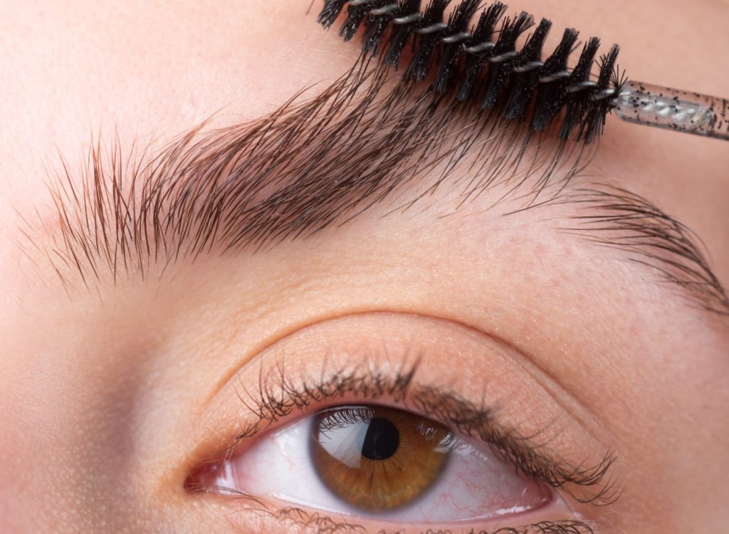 Womans eyebrows. Beautiful girl with eyebrow brush. Girl with natural make up. Eyebrow correction. Macro close up of brows